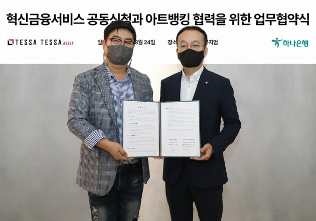 하나은행은 24일 오후 서울 성수동에 위치한 미술품 조각투자 플랫폼 테사 본사에서 아트뱅킹 활성화를 위한 업무협약을 체결했다. 이날 협약식에 참석한 김기석 하나은행 자산관리그룹 부행장(사진 오른쪽)이 김형준 테사 대표(사진 왼쪽)와 업무협약서를 들고 기념촬영을 하고 있다. 하나은행 제공