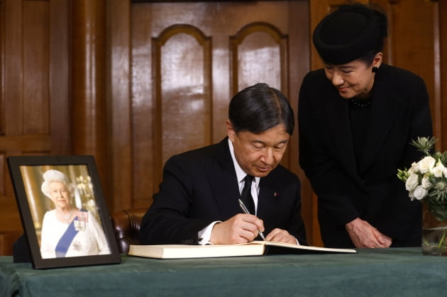 나루히토 일왕이 지난 19일(현지 시각) 영국 런던 처치하우스에서 엘리자베스 2세 여왕을 애도하는 조문록을 작성하고 있다. 오른쪽은 마사코 일본 왕비. /AFP=연합