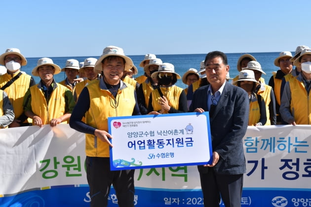 김진균 Sh수협은행장(맨 앞줄 왼쪽)이 지난 24일 강원 양양군 낙산해수욕장에서 조성욱 양양군수협 상임이사에게 어업활동지원금을 전달하고 있다.  Sh수협은행 제공