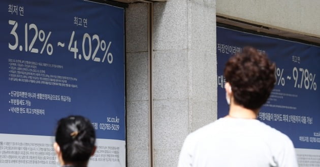 시민들이 지난달 12일 서울 시내 한 은행에 내걸린 상품 안내 현수막을 보며 지나가고 있다./ 연합뉴스