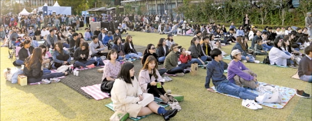 ‘청춘, 커피 페스티벌’에 참여한 시민들이 서울 롯데월드타워 잔디광장에서 공연을 보며 여유를 만끽하고 있다. (2019년 행사) 