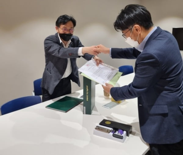 조현흠 노틸러스인베스트먼트 이사(오른쪽)가 강석명 픽셀로 대표(왼쪽)에게 홍콩법인 설립 서류를 전달하고 있다. 제공=노틸러스인베스트먼트