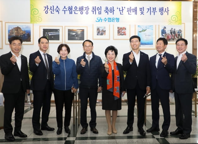 수협은행은 지난 24일 서울 신천동 본사 1층 로비에서 ‘강신숙 은행장 취임 축하화환(난) 판매 및 기부행사’를 열었다. 강신숙 수협은행장(왼쪽 다섯 번째)과 임직원들이 손 하트를 만들어 보이고 있다. 수협은행 제공