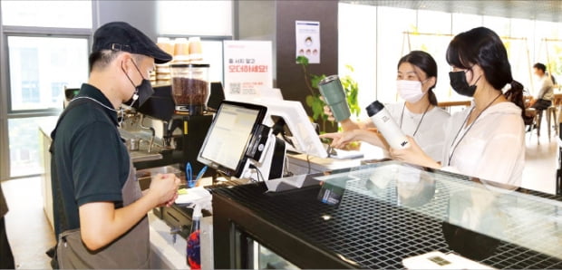DL이앤씨 직원이 서울 종로구 돈의문 디타워에 위치한 D라운지카페에서 일회용 컵 대신 개인 컵을 사용해 음료를 주문하고 있다.  DL그룹 제공 