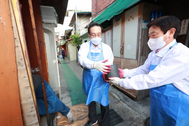 우리금융그룹 우리금융미래재단 손태승 이사장(왼쪽)과 임직원들이 지난 14일 서울 영등포구 쪽방촌을 방문해 연탄을 옮기고 있다.(사진=우리금융미래재단)