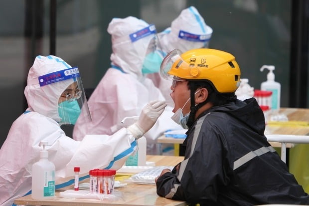  중국 수도 베이징 차오양구에서 한 의료인이 코로나19 검사를 위해 주민에게서 검체를 채취하고 있다. /연합뉴스(XINHUA)