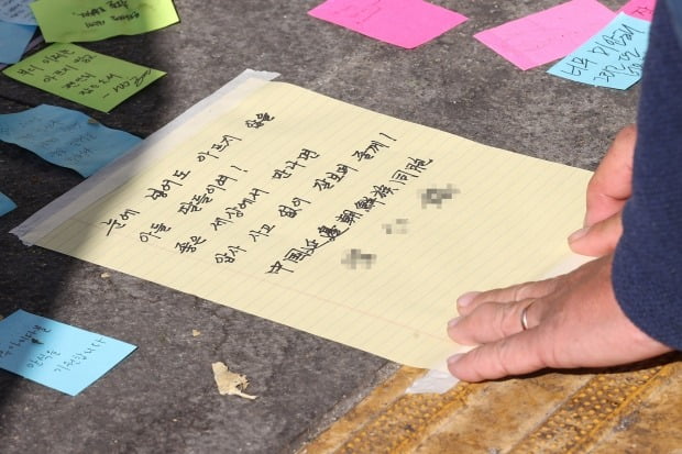 지난 2일 서울 용산구 이태원역 1번 출구 앞 참사 추모 공간을 찾은 시민이 편지를 붙이고 있다. 사진=연합뉴스