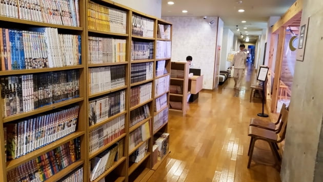 만화책을 비롯한 많은 종류의 도서 / 목욕탕 카페 시설에서 휴식을 취하고 있는 고객들. / JAPAN NOW