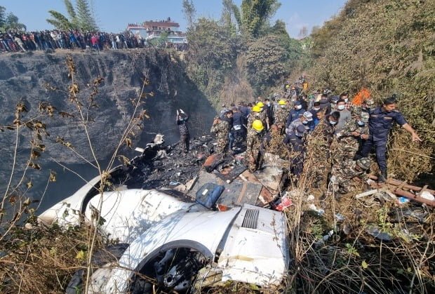 항공기 잔해가 남아있는 네팔 포카라에서 구조요원들이 희생자를 옮기고 있다. 사진=뉴스1