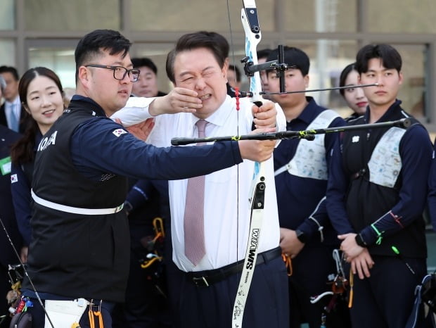 윤석열 대통령이 14일 충북 진천선수촌에서 열린 '2023 대한민국 체육비전 보고회'를 마친 뒤 양궁장에서 김우진, 최미선 선수가 지켜보는 가운데 화살을 쏘고 있다. 연합뉴스