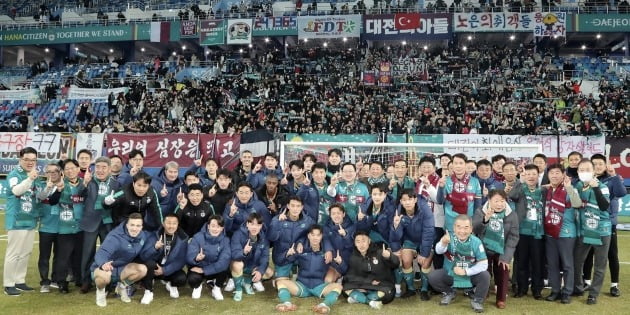 함영주 하나금융그룹 회장(사진 앞에서 3번째줄 가운데 왼쪽)과 이장우 대전시장(사진 앞에서 3번째줄 가운데 오른쪽)이 선수단 및 그룹 관계자들과 홈 개막전 승리를 축하하는 기념사진을 촬영하고 있다.  /하나금융 제공.