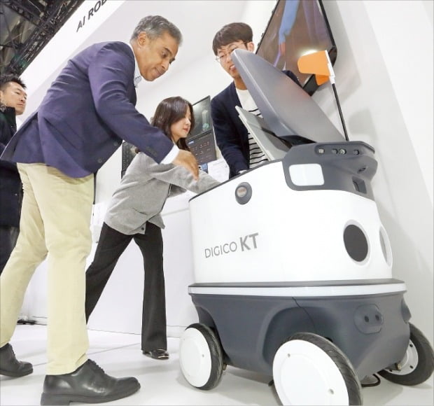 KT는 28일 MWC 2023에서 로봇 관제 플랫폼 ‘로봇 메이커스’와 자율주행 배송 로봇을 공개했다. 관람객들이 배송 로봇 안을 들여다보고 있다.  KT  제공 