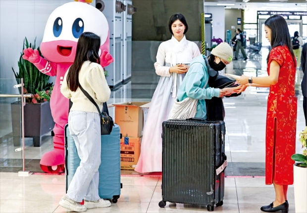 한국공항공사 관계자들이 27일 김포공항에서 김포~베이징·상하이 노선 운항 재개를 기념해 입국자들에게 기념품을 나눠주고 있다. 코로나19 이후 3년 만의 운항 재개로 한·중·일 수도를 잇는 ‘베세토(베이징·서울·도쿄) 비즈니스 실크로드’가 모두 정상화됐다. 김범준 기자 