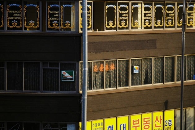 건물 3층 창문으로 보이는 네온사인과 사진 현상소임을 짐작케 하는 후지필름·코니카 부착물 (사진=망우삼림)