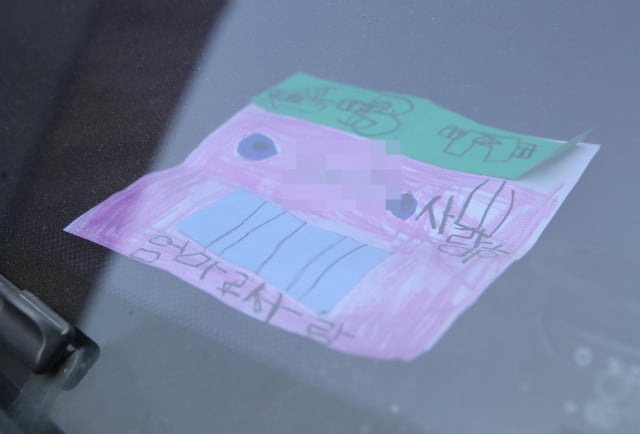지난 18일 인천시 미추홀구 한 주택에서 숨진 채 발견된 일가족 소유 차량에 아이가 쓴 것으로 보이는 쪽지가 놓여 있다.  / 사진=연합뉴스