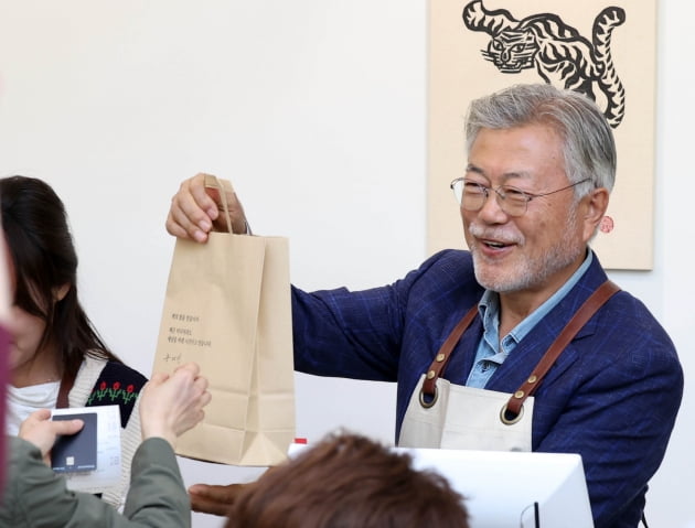 문재인 전 대통령이 26일 오후 경남 양산시 하북면 자신의 책방 '평산책방'에서 계산 업무를 하며 책을 손님에게 건네고 있다. /사진=연합뉴스