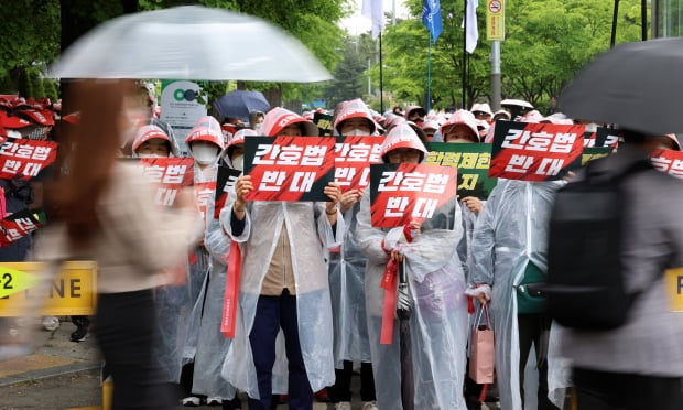  25일 오후 서울 여의도 국회 앞에서 열린 간호법저지 전국라바 카지노 대표자 연가투쟁에서 시민들이 피켓을 든 참가자 앞을 지나고 있다. /사진=연합뉴스