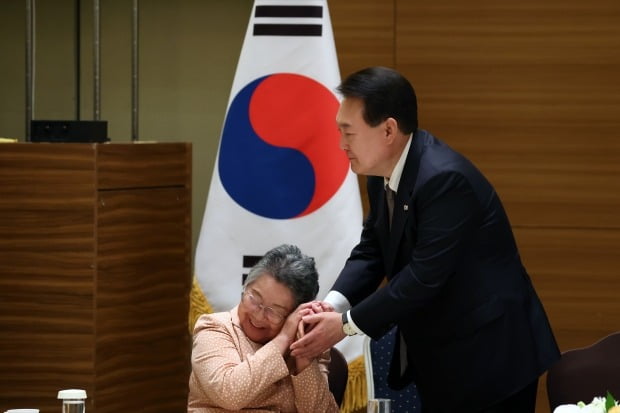 박남주 전 한국원폭피해대책특별위원회 위원장(91세)이 19일 일본 히로시마에 한 호텔에서 열린 한국인 동포 원폭 피해자 간담회에서 윤석열 대통령의 두 손을 자신의 뺨에 갖다 대고 어루만지는 모습. 뉴스1