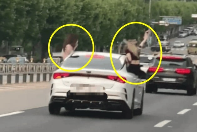 도로 한복판에서 달리는 차량 문에 걸터앉은 여성 두 명의 모습. /사진=연합뉴스