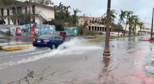 괌 강타한 '슈퍼 태풍'으로 침수된 거리 지나가는 자동차. 연합뉴스