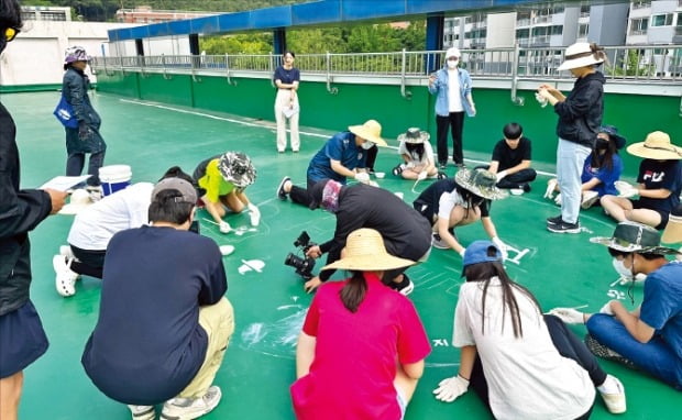 지난 5일 경기도 군포에서 지붕·옥상 온도 낮추기 사업에 참여한 학생들이 건물 옥상을 쿨루프 페인트로 칠하고 있다. /한국지역난방공사 제공 