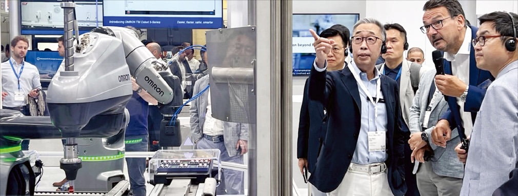 박지원 두산그룹 부회장(왼쪽)이 28일(현지시간) 독일 뮌헨에서 열린 ‘오토매티카 2023’에서 한 로봇업체 관계자에게 질문하고 있다.  /두산 제공
 