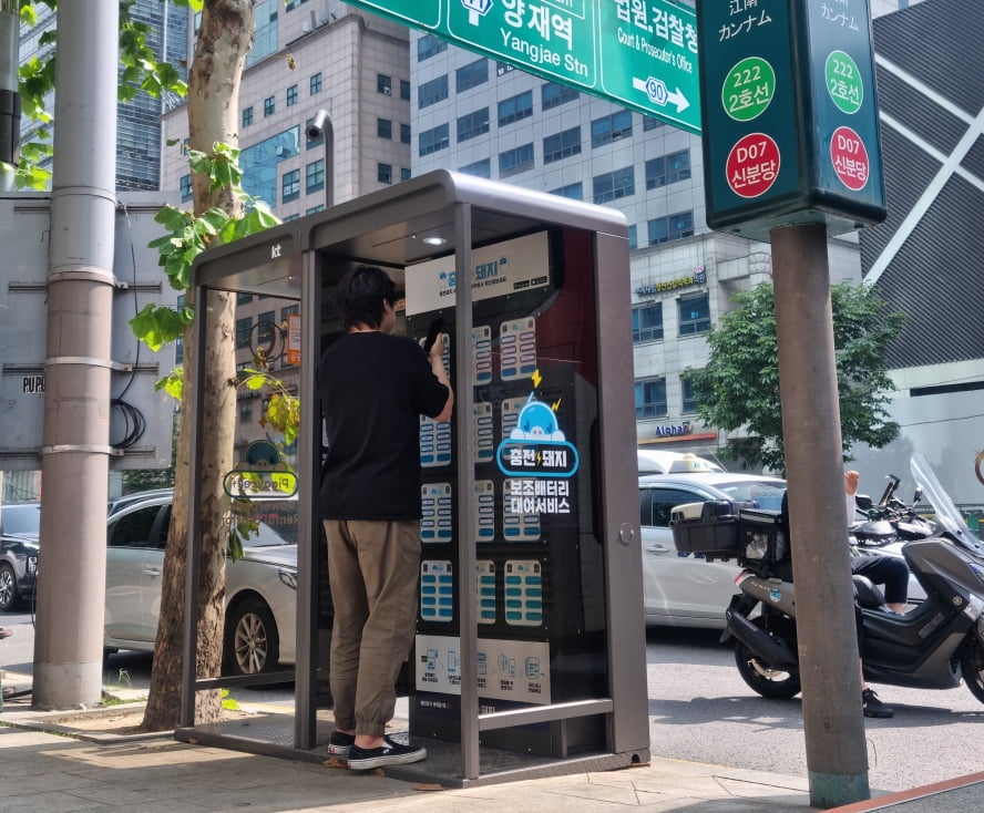 서울 강남구 강남역사거리 공중전화 부스에 설치된 ‘충전돼지’ 전용부스에서 시민이 보조배터리를 대여하고 있다. 백퍼센트 제공  