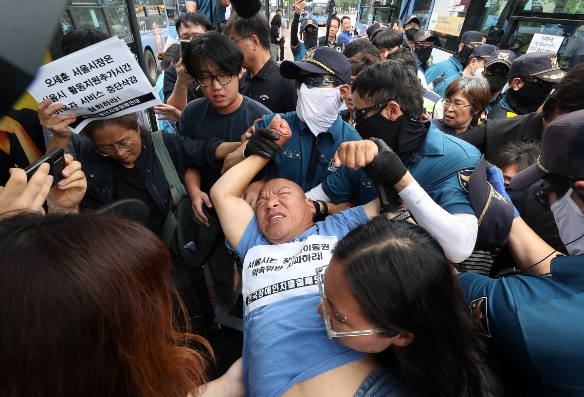 전국장애인차별철폐연대(전장연) 회원들이 17일 오후 서울 종로구 혜화동로터리 버스 정류장에서 전장연 탄압 중단을 촉구하며 '계단 버스' 탑승을 시도했으나 경찰들에 의해 강제 하차되고 있다. /사진=뉴스1