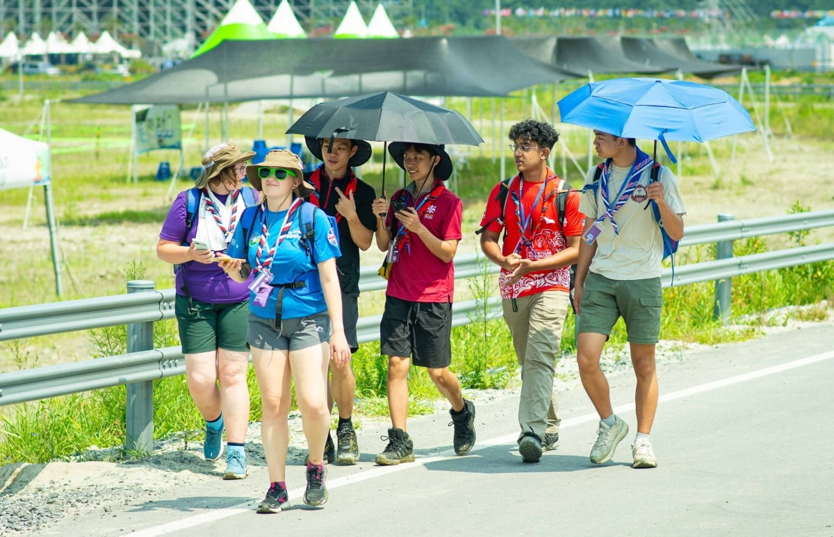 2023 새만금 세계잼버리에 참가한 스카우트 대원들이 1일 양산으로 더위를 피하며 걸어가고 있다./세계스카우트연맹 제공