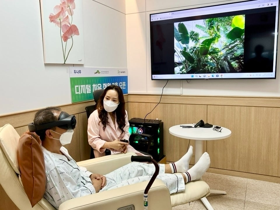 디지털 치유 정원 2호점이 설치된 '서울재활병원'에 입원 중인 환자가 국립세종수목원을 촬영한 VR 영상을 직접 체험하고 있다. / 사진=두나무