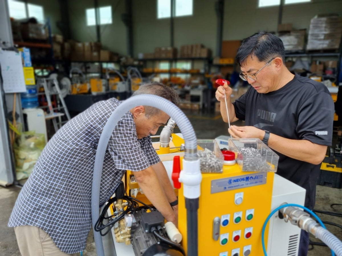 경남 창원의 네오스에서 근무하는 60대 엔지니어들이 국산화에 성공한 CNC 공작기계용 ‘이동형 절삭유 탱크 청소기’ 성능을 점검하고 있다. 네오스 제공
 