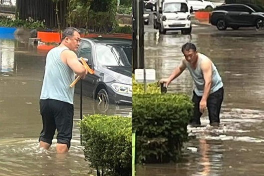 23일 충북 청주시 충북대학교 앞 개신오거리 도로에서 한 시민이 기습폭우로 잠긴 도로의 배수구를 뚫고 있다. 이 시민은 충북도의원으로 알려졌다. / 사진=보배드림