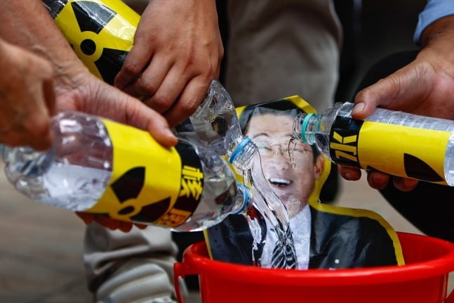 지난 23일 홍콩의 일본 총영사관 앞에서 홍콩 어부들이 후쿠시마 오염수 방출에 반대하는 시위를 벌이며 일본 총리의 사진에 물을 붓고 있다. EPA 연합뉴스.