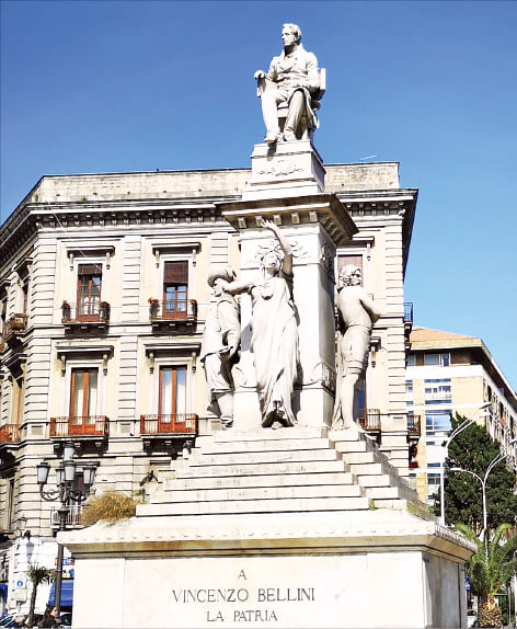 카타니아 스테지코로광장에는 오페라 작곡가 빈첸초 벨리니 기념 석상이 서 있다. ‘노르마’ 등 대표 작품 속 상징들이 그를 떠받치고 있다.
 