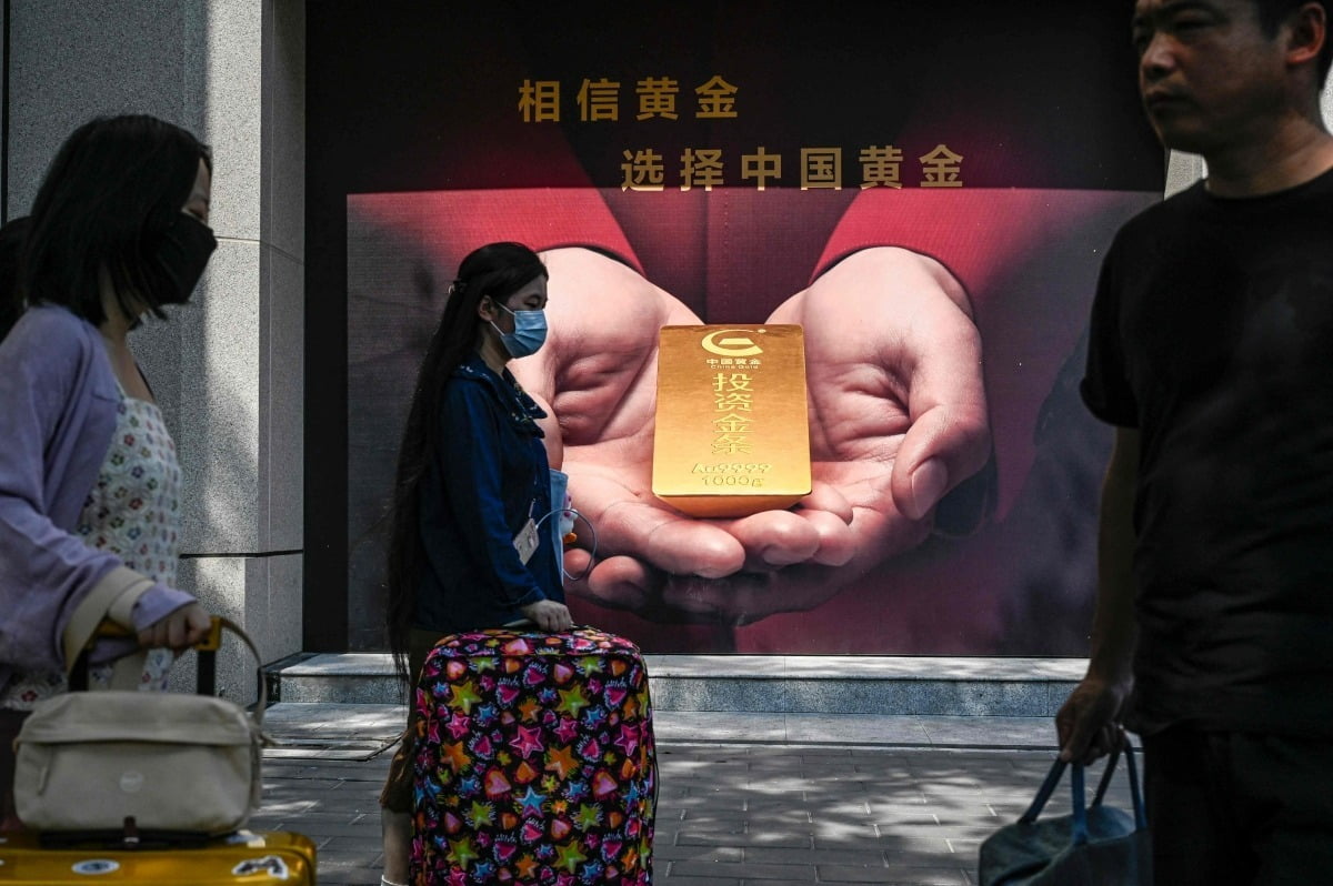 중국 베이징 시민들이 지난 15일 한 금은방 앞을 지나가고 있다. /AFP