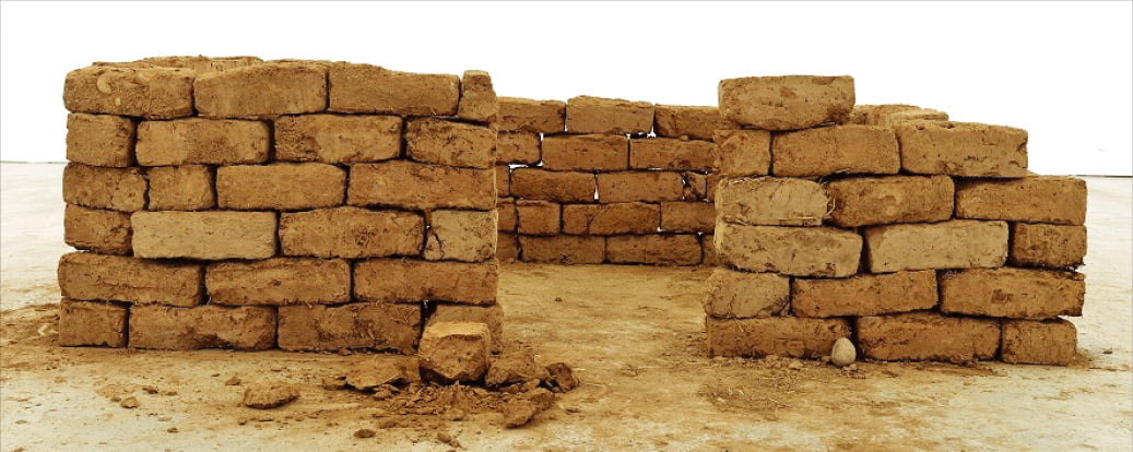 안젤름 키퍼의 2022년 작품 ‘지금 집이 없는 사람은 이제 집을 짓지 않습니다’. 홍토와 짚으로 구성한 벽돌 118개로 만들었다. 턱없이 부족한 쉼터에 대한 안타까움을 그렸다.   헤레디움 제공 