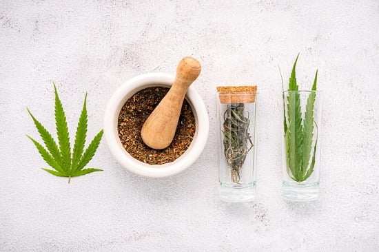 Glass bottle of cannabis oil with white mortar and hemp leaves set up  on concrete background.