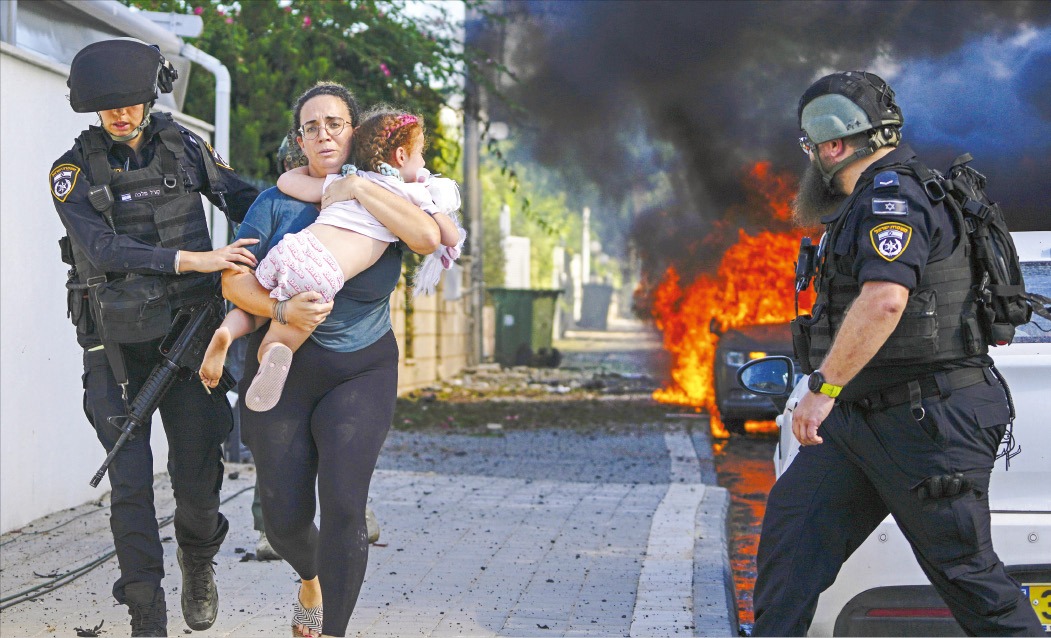 < ‘아가야 조금만 참아’ > 7일(현지시간) 팔레스타인 무장 정파 하마스의 로켓 공격을 받은 이스라엘 남부 아슈켈론에서 아이를 안은 한 여성이 경찰의 도움을 받아 대피하고 있다.  AP연합뉴스 