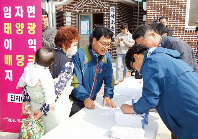 전남 신안군 관계자가 지난 4월 임자도 주민에게 태양광 이익 배당금을 나눠주고 있다.  신안군 제공 