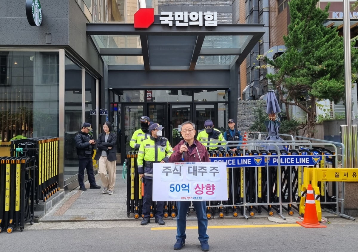 지난 14일 국민의힘 당사 앞에서 '대주주 양도세 기준 50억 상향' 피켓을 들고 시위를 한 정의정 한투연 대표 모습. 사진=한투연