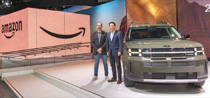 현대자동차와 아마존은 16일 ‘2023 LA 오토쇼’에서 전략적 파트너십을 맺었다. 마티 말릭 아마존 부사장(왼쪽)과 호세 무뇨스 현대차 사장이 ‘디 올 뉴 싼타페’ 앞에서 기념촬영을 하고 있다.    /현대차 제공 