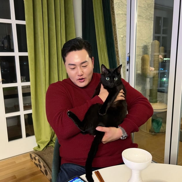 Park Soo-hong and Choi Ji-man show off their pet cat Dahong in their arms.