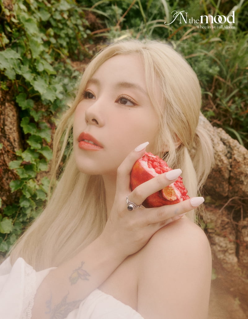 Wheein, holding a pomegranate in her hand