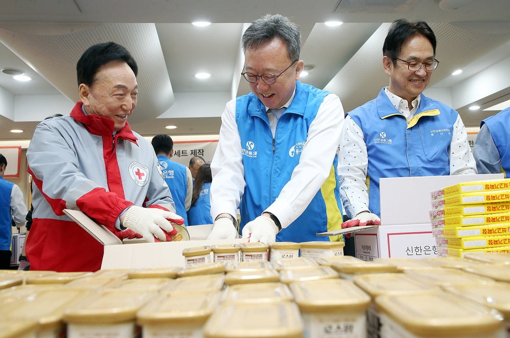 서울 남산동3가에 위치한 대한적십자사 서울사무소에서 진행된 ‘긴급비상식량세트’ 제작 봉사활동에서 정상혁 신한은행장(가운데)과 김철수 대한적십자사 회장(왼쪽), 신한은행 임원들이 식량세트를 제작하고 있는 모습. 신한은행 제공