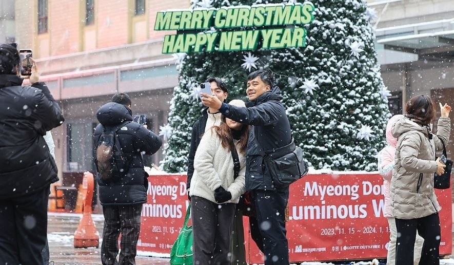 지난 25일 오전 서울 중구 명동을 찾은 외국인 관광객이 크리스마스트리 앞에서 기념 촬영하고 있다. 연합뉴스