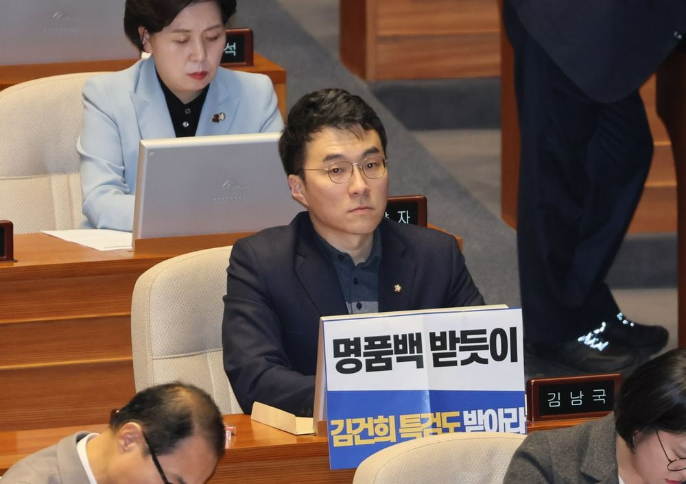 김남국 무소속 의원이 28일 오후 국회 본회의에서 김건희 여사 특검법 수용을 촉구하는 손팻말 뒤에 앉아있는 모습. 연합뉴스