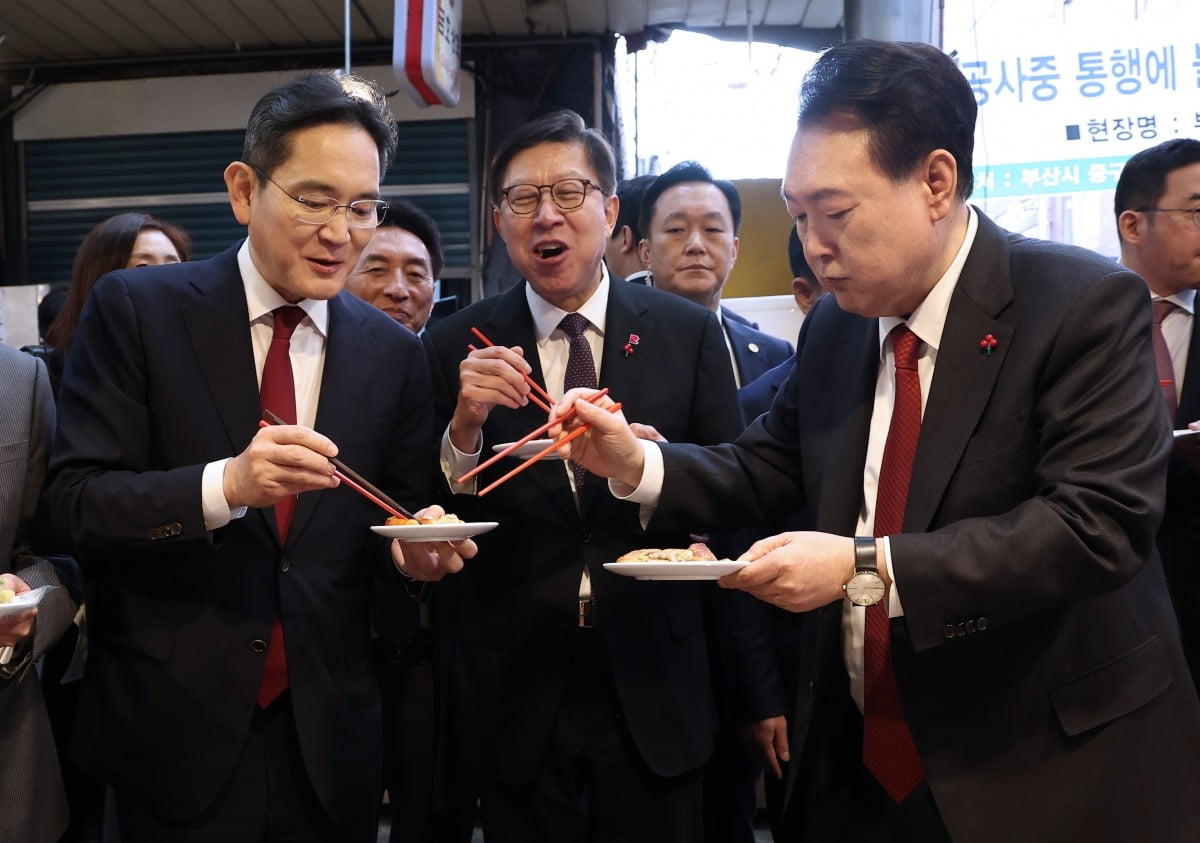 윤석열 대통령이 6일 부산 중구 깡통시장에서 이재용 삼성전자 회장에게 빈대떡을 건네고 있다.  사진=연합뉴스