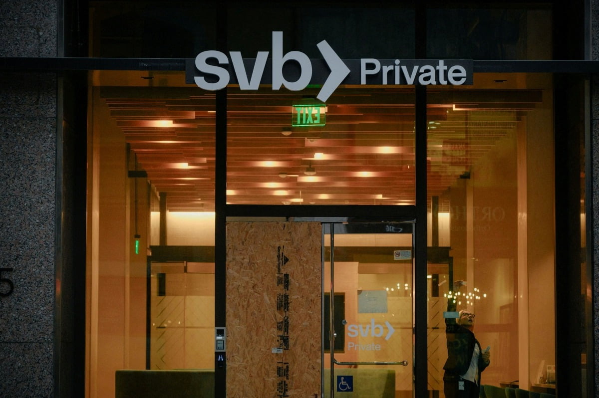 실리콘밸리은행(SVB)이 파산하고 사흘 뒤인 지난해 3월 13일 미국 캘리포니아주 샌프란시스코 시내 한 SVB 지점에서 직원이 창문에 붙은 테이프를 떼어내고 있다. /로이터