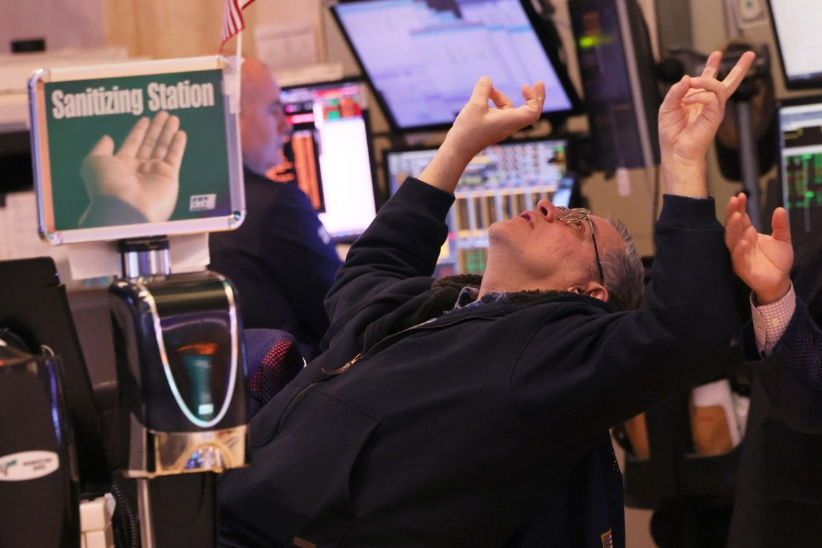 S&P지수와 다우존스가 사상 최고치를 기록한 지난달 22일(현지시간) 미국 뉴욕증권거래소에서 한 딜러가 고개를 젖히고 손으로 V자를 그리고 있다. /AFP