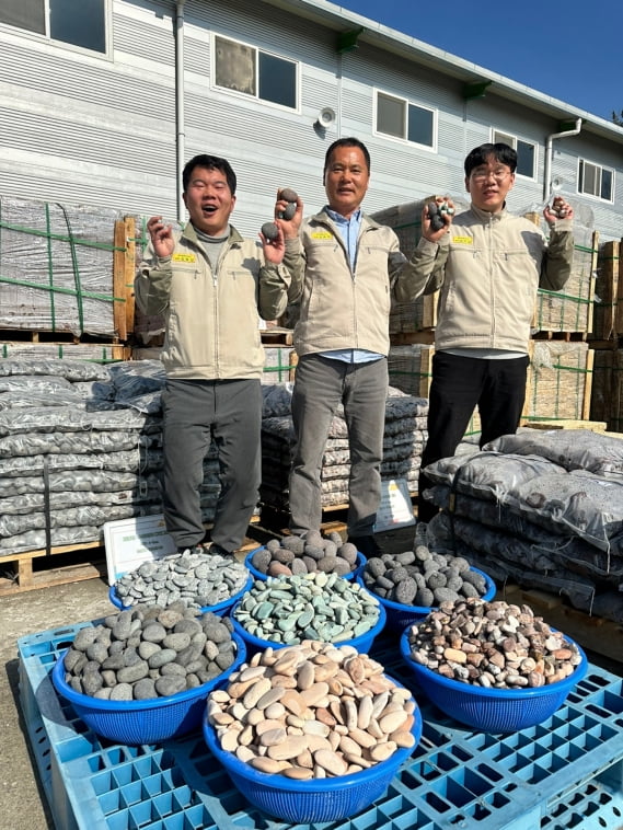 온양석산의 김화옥 대표(가운데)와 김명성 대리(왼쪽), 김진성 대리(오른쪽) 삼부자가 반려돌의 주재료인 에그스톤을 들어보이고 있다./아산=민지혜 기자